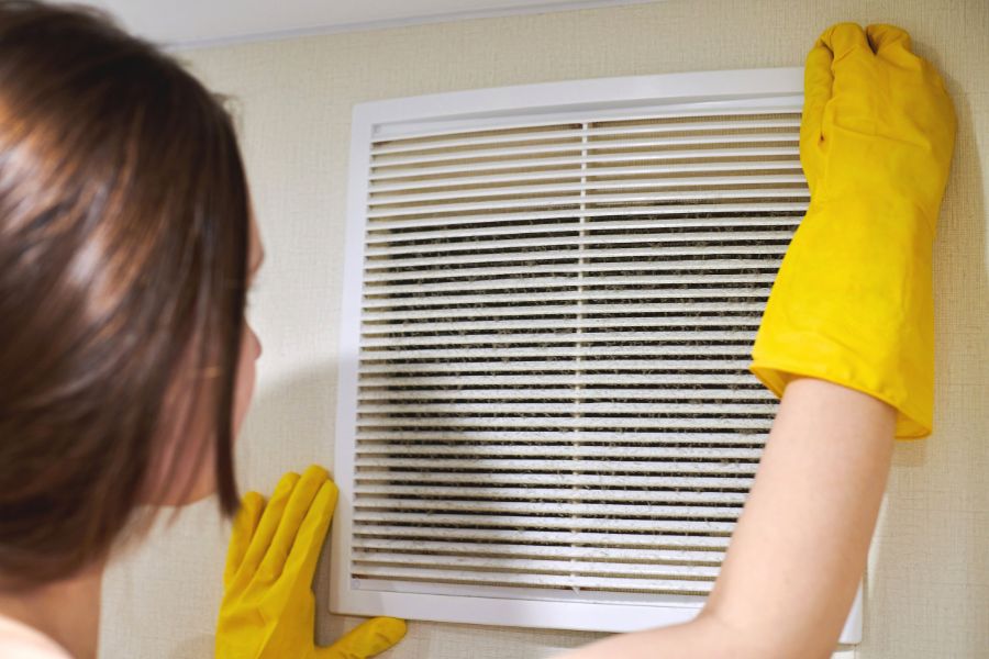 Woman with yellow gloves fixing a duct